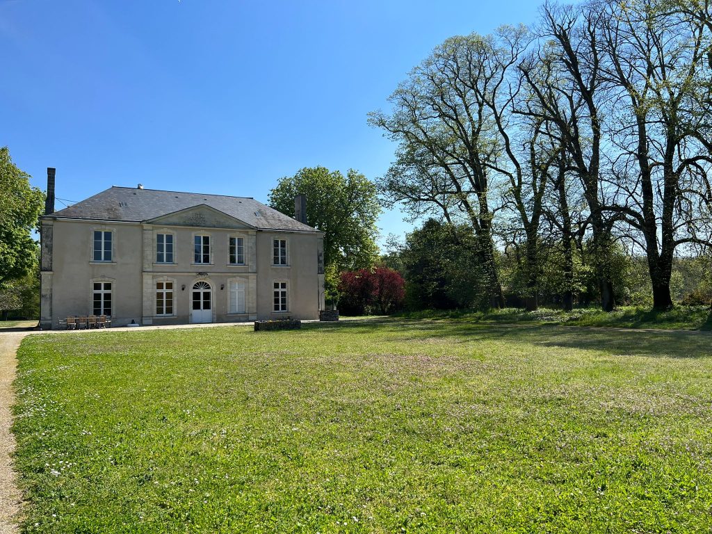 a large White House with big windows with a green lawn in front and clear blue sky above